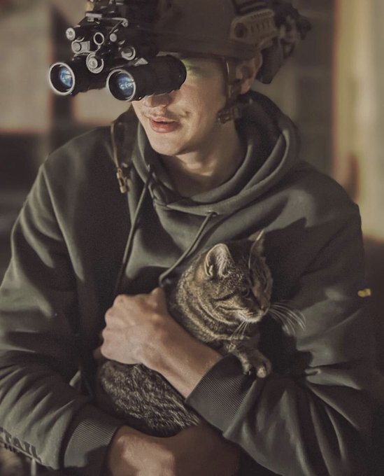 Ukrainian soldier holds a small tabby cat.