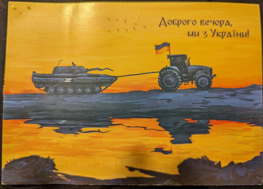 Postcard from Kyiv, tractor towing a tank with caption in Cyrillic 'Good evening, we are from Ukraine.'