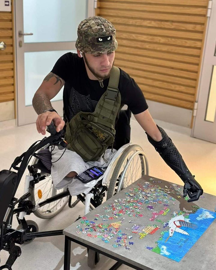 Ukrainian soldier Denys Kryvyenko uses a prosthetic arm to assemble a jigsaw puzzle.
