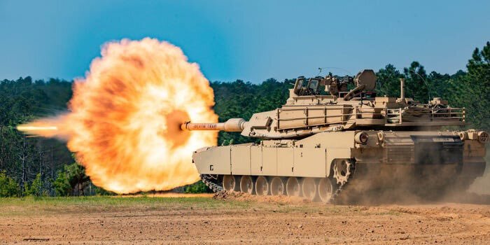 Artistic shot of an Abrams tank firing a round.