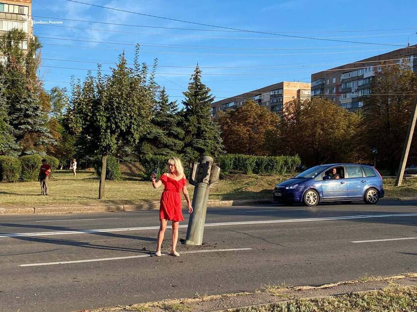 Woman in red dress takes selfie with unexploded Russian missile.