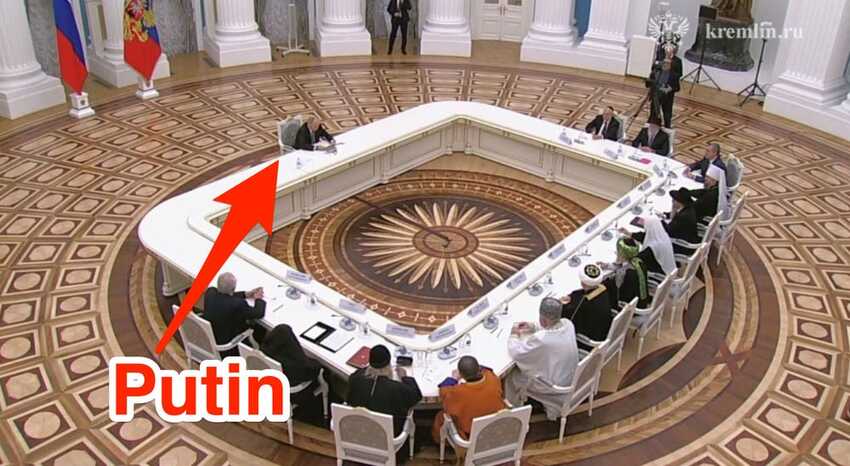Putin sitting at a massive table far far away from all other people.