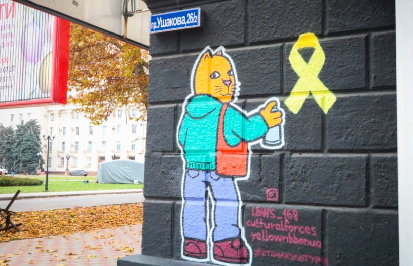 Graffiti showing a cat drawing a yellow ribbon, a symbol of a Ukrainian resistance movement.