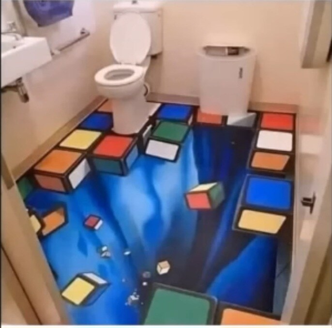A rug in a bathroom which shows cubes falling out of the floor into a colorful void.