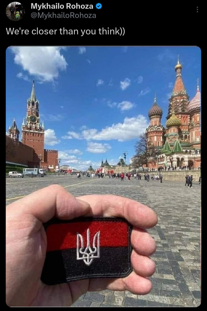 Someone took a photo of themselves holding a Ukrainian flag (with tryzub) in Red Square, caption 'We're closer than you think.'
