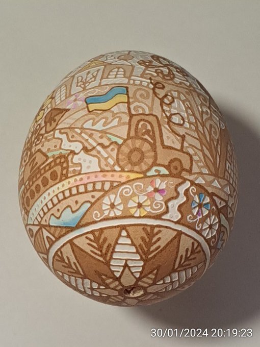 A non-traditional prysanky egg showing a tractor towing a tank.