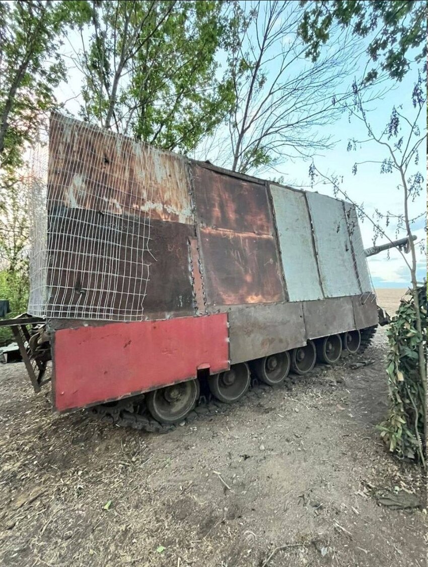 A rather sad-looking Russian vehicle with steel plates and fencing on it.